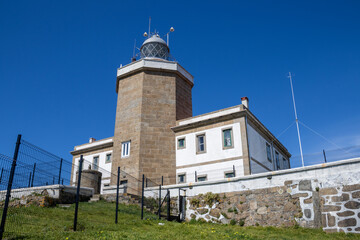 Finisterre Lighthouse on a rocky cliff in Galicia, Spain, overlooking the Atlantic Ocean at sunset....