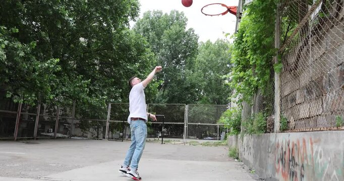 Father throws basketball ball up in air playing with daughter on urban playground. Man and preteen girl show family bonding and active lifestyle