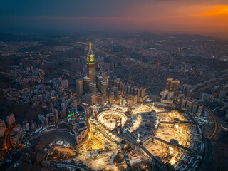 Aerial view at night of the illuminated Grand Mosque and Abraj Al-Bait Clock Tower in Mecca,...