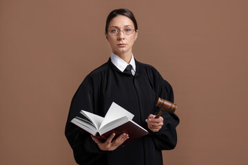 Judge with mallet and book on light brown background