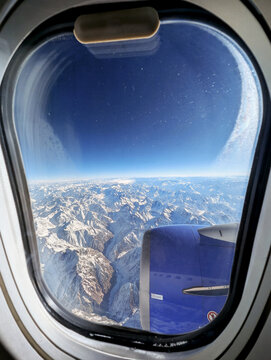 Fototapeta Scenic view of snow-covered mountains from airplane window