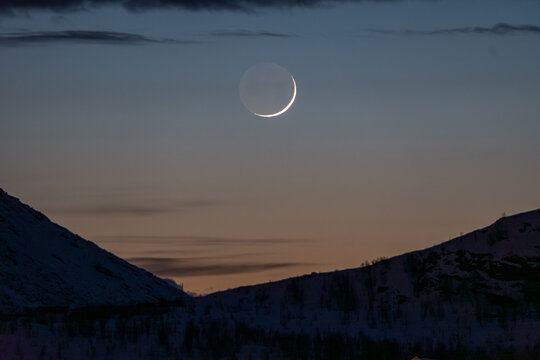 Crescent moon over twilight nordic landscape