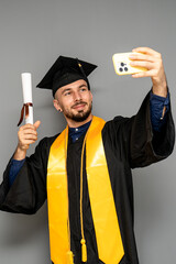 Happy graduate taking a selfie with diploma and smartphone