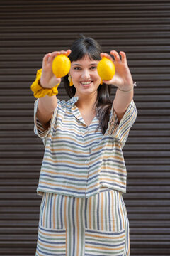 Smiling woman holding lemons in striped outfit