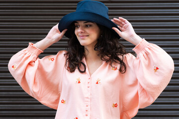 Woman wearing a stylish blue hat and pink blouse
