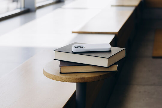 Smartphone and books on a wooden bench indoors