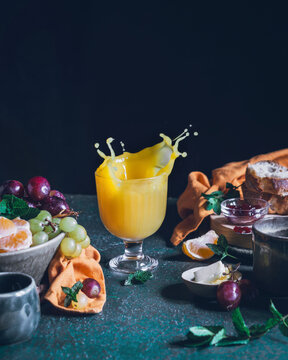 Fresh juice splash with fruits and bread on table