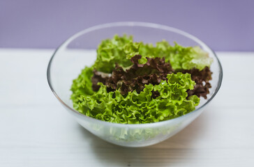 Fresh salad in a bowl on a purple background with copy space. Local food concept.