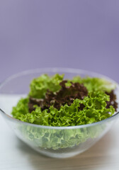 Fresh salad in a bowl on a purple background with copy space. Local food concept.