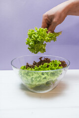 Fresh salad in a bowl on a purple background with copy space. Local food concept.