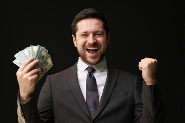 Happy greedy banker with dollar banknotes on black background