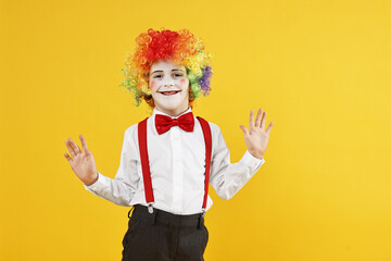 Happy little boy dressed like clown on yellow background, space for text. Surprise party