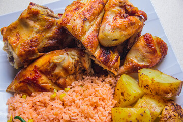 A vibrant dish featuring juicy grilled chicken served with flavorful rice and crispy potatoes,...