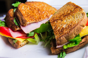 A delectable toasted sandwich filled with fresh ingredients including lettuce, tomatoes, and ham, showcasing a perfect blend of colors and textures ideal for a tasty meal.