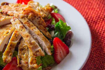 This close-up captures the delightful textures and colors of a grilled chicken salad adorned with strawberries, emphasizing natural beauty and culinary artistry.