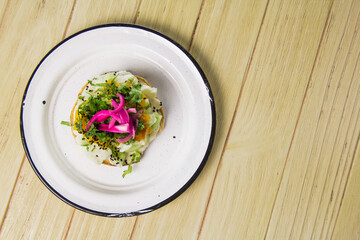 A fresh seafood tostada arranged on a single plate, featuring colorful toppings such as pickled onions, cucumber, and herbs, emphasizing healthy dining choices.