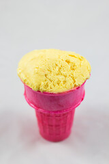 A vibrant yellow scoop of ice cream sits delightfully in a pink cone, showcasing a fun and colorful...