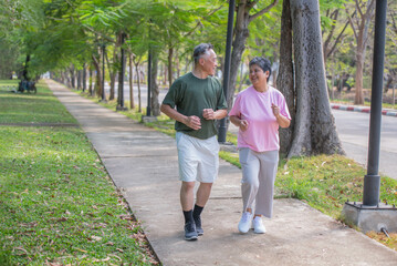 Obraz premium A retired couple jogging in a park takes care of their health by exercising regularly.