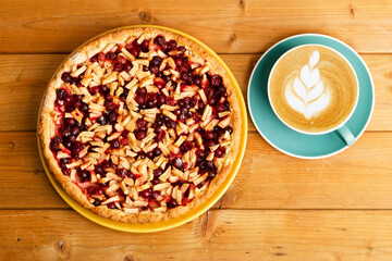 Homemade berry and apple pie and cup of coffee cappuccino on wooden table. Top view.