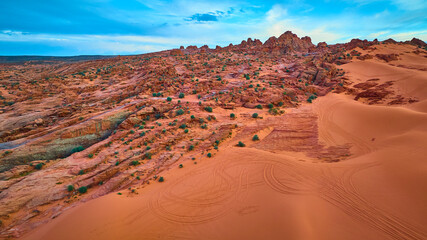 Aerial Red Rock Outcrops and Sand Dunes with Tire Tracks Motion Perspective