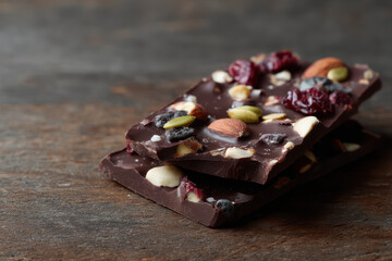Dark chocolate bark with nuts and seeds on wooden surface