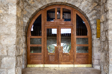 Massive wooden doors with high open arches of an old historical building. Most of the doors are covered with stained glass windows