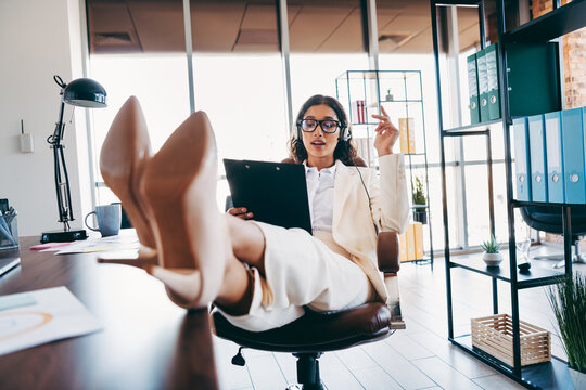 Charming businesswoman in formal attire working in a modern office setting, engaged during a call, exuding efficiency and charm