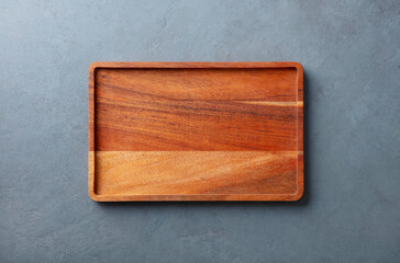 Wooden cutting board or serving board, top view. Copy space for design elements or text. Grey stone background. Close up.
