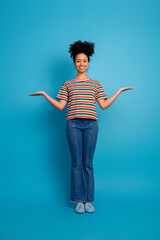 Young woman smiling in fashionable striped shirt presenting open palm gesture on turquoise background