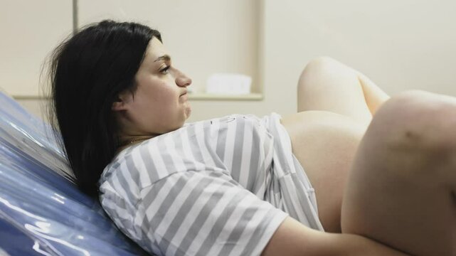 
A pregnant woman in active labor, enduring strong contractions while medical personnel help her deliver the baby. The concept of childbirth and professional assistance.