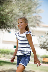 Joyful Girl with a Striped Top Happily Walking Outdoors.