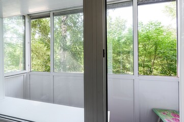 Fototapeta premium View from a balcony with white frames overlooking lush green trees.