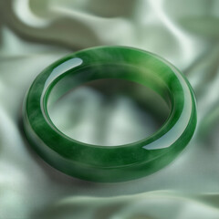 Green jade bangle resting on soft satin fabric background  