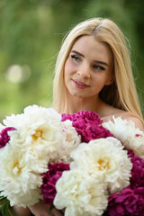 Fototapeta premium girl walking in the park with a bouquet of peonies