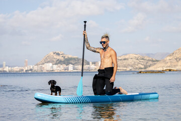 Man paddle surfing with a dog.