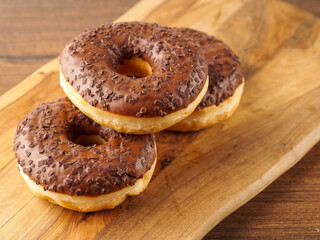 Sweet tasty chocolate donuts on wooden board. Popular desert and snack. Fine bakery product.