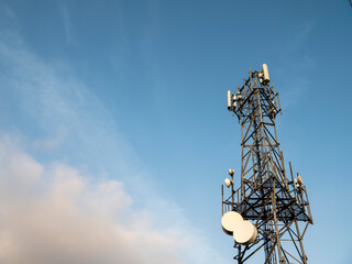 A tall tower with many antennas on top. The sky is blue and clear. The tower is a cell phone tower...