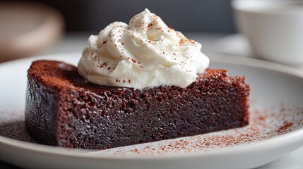 Swedish sticky chocolate cake slice with whipped cream on white plate