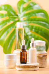 Set of natural cosmetics serum, cream and micellar water with monsterra leaves on pastel blurred background