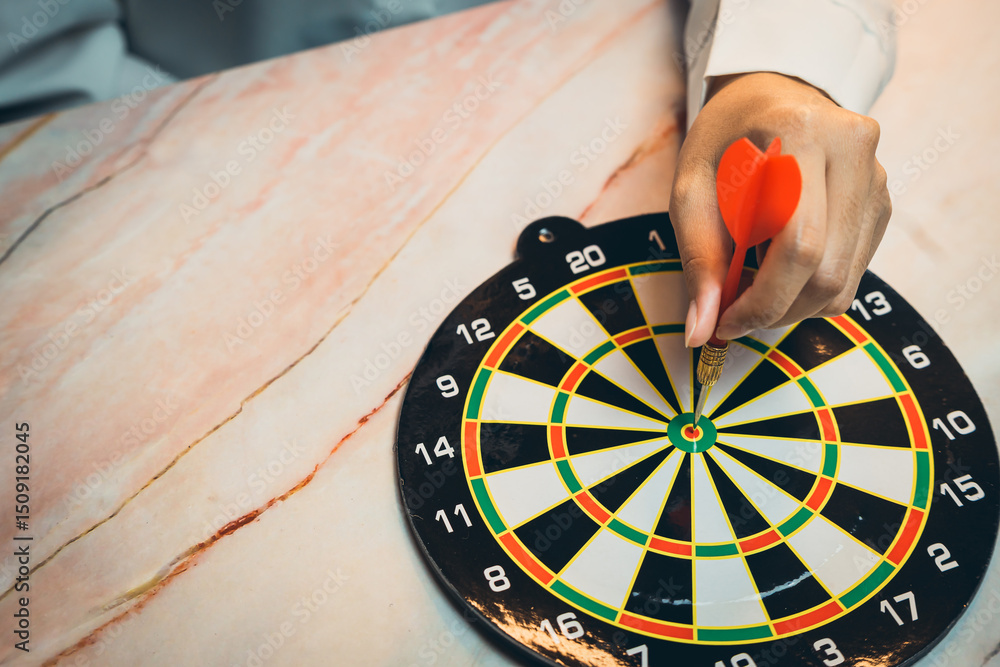 Poster goal concept. person aiming dart at bullseye on dartboard, focused hand with dart and targeting prec