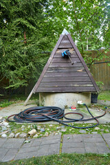 Garden hose lying on the ground next to a well in the garden