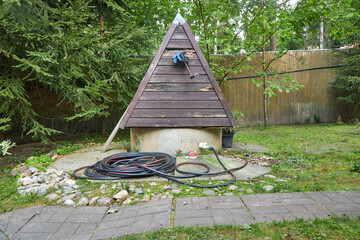 Garden hose lying on the ground next to a well in the garden