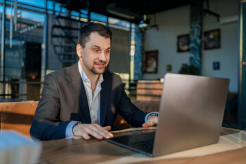 Fototapeta premium Businessman Engaged with Laptop in Modern Cafe Setting