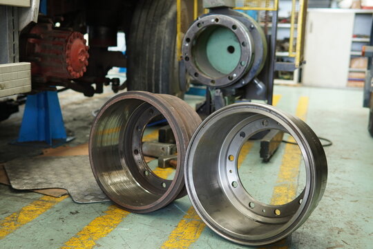 Old and new brake drums in a truck repair shop. Car repair, maintenance. Worn, rusty brake drum and clean, polished one on the right