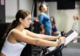 Fototapeta premium Caucasian woman training on exercise bike in gym