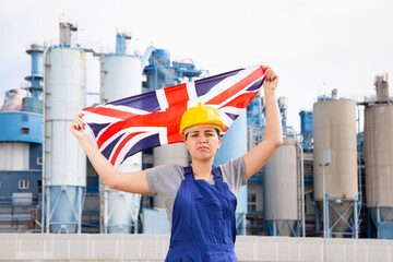 Upset disappointed young female engineer in helmet waving state flag of Great Britain during strike...