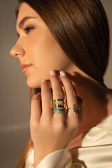 girl's face in profile, hand near face, rings with Ukrainian symbols on fingers