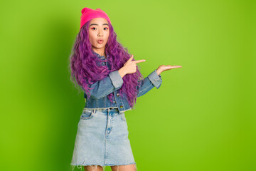 Young woman in fashionable casual attire presenting with hand gesture in front of bright lime green background