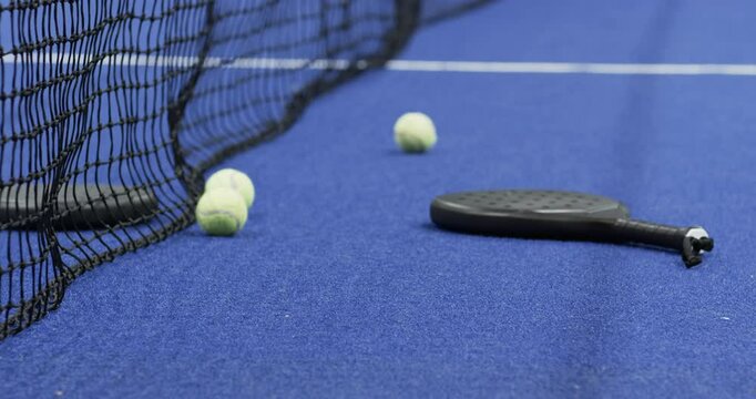 Padel racket and tennis balls on indoor court, ready for exciting match, copy space