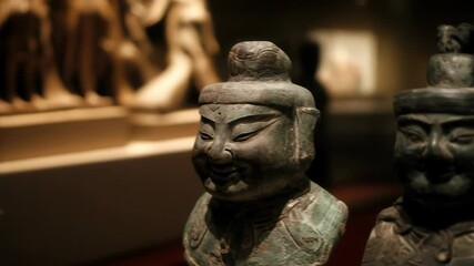 Bronze statues of ancient Chinese military figures stand in a dark museum on display for visitors to see the old artifacts.